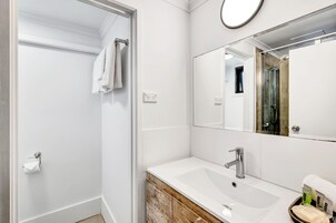 A modern bathroom with a white sink, a mirror, and a shower area.