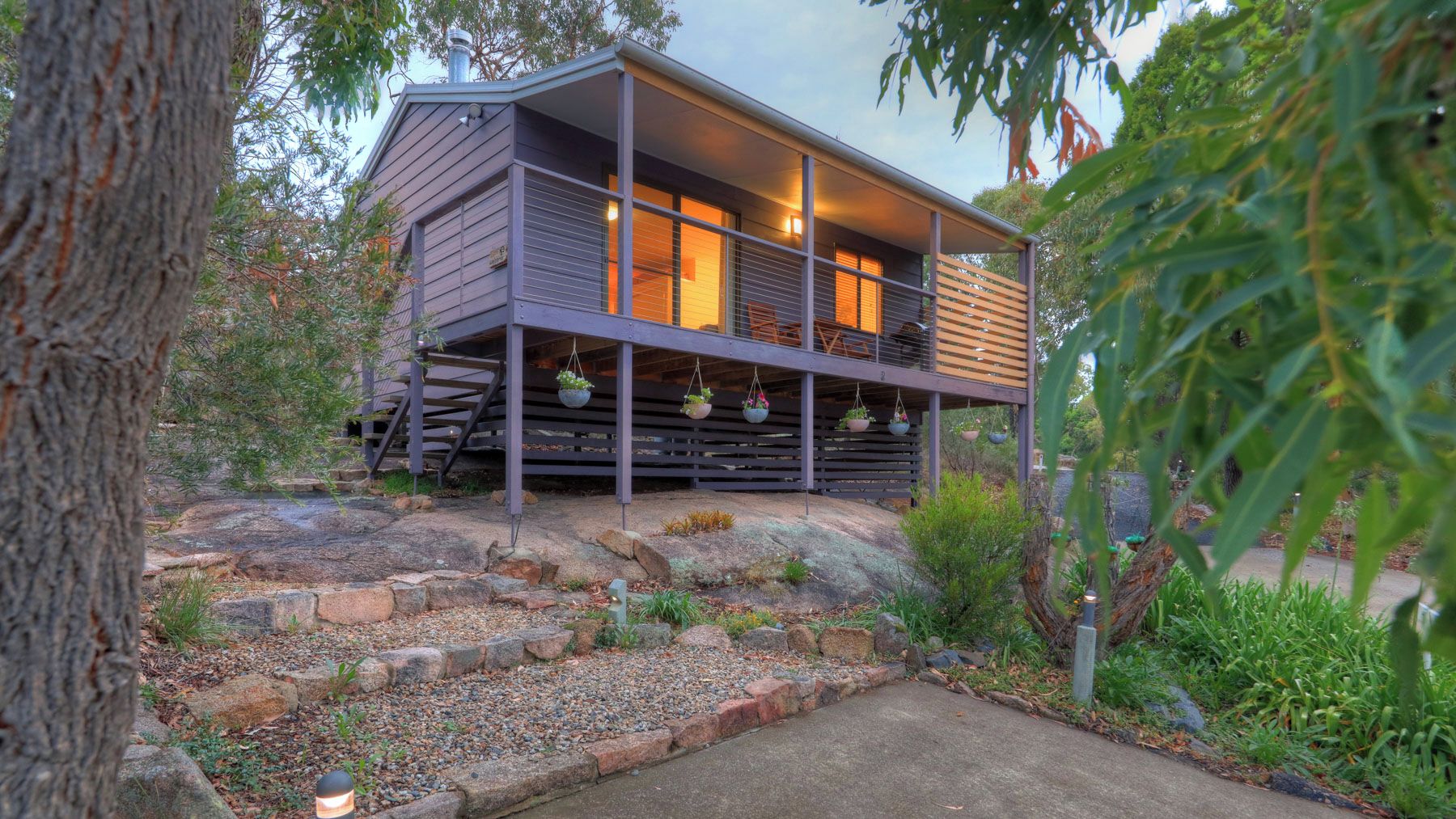 A cabin with a wooden deck and hanging planters.