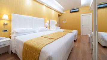 A hotel room with two beds, a bedside table, and a wardrobe.