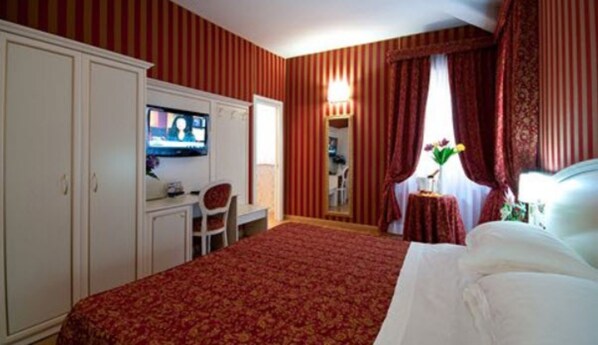 A hotel room with a bed, a desk with a chair, a television, and a window with curtains. - Trevi 41 Hotel (Rome)