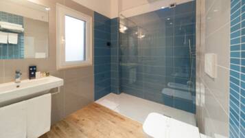 Une salle de bain moderne avec une douche à l’italienne en verre, un lavabo blanc et un plancher en bois.