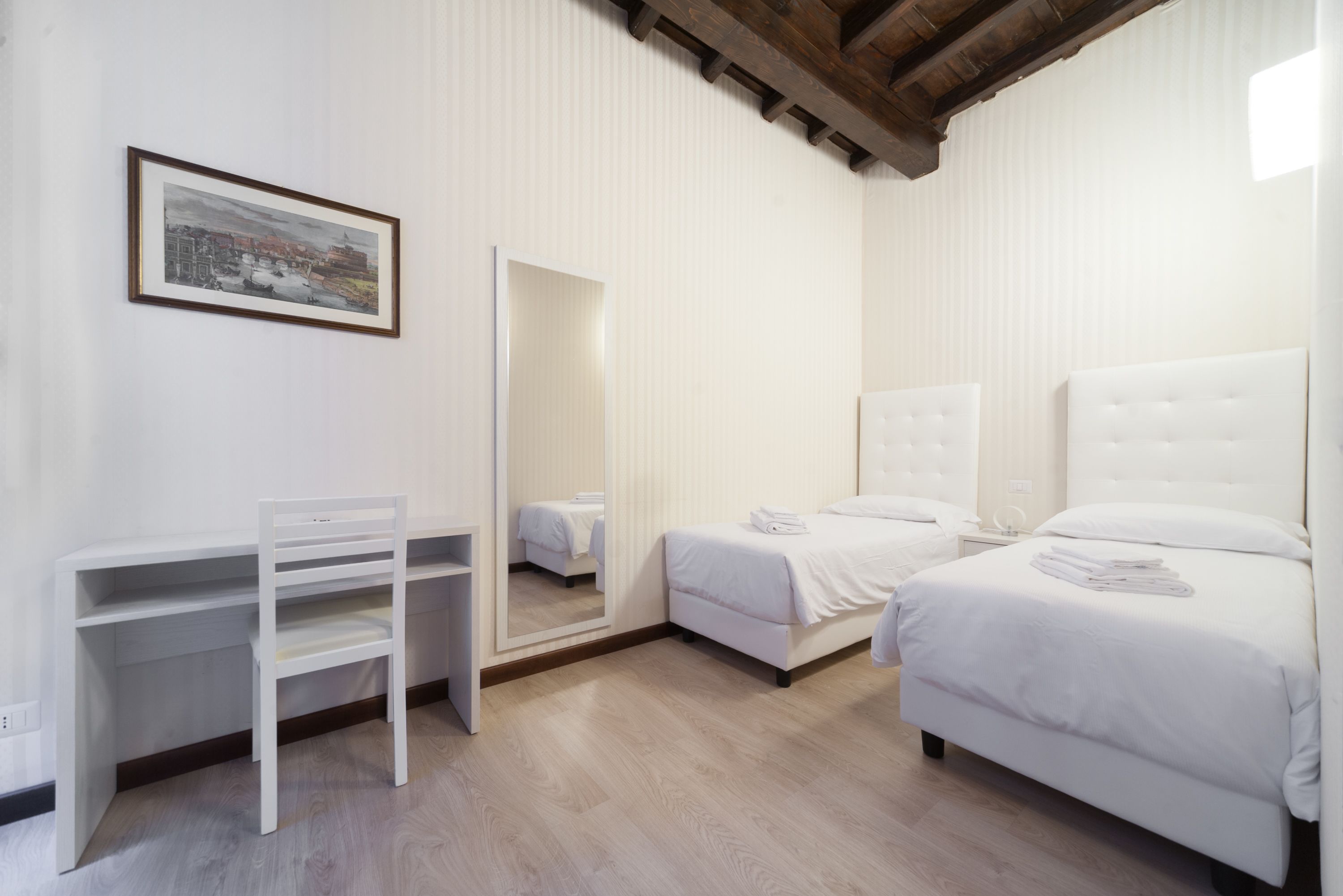 Ein Hotelzimmer mit Bett, Schreibtisch, Stuhl und Spiegel.