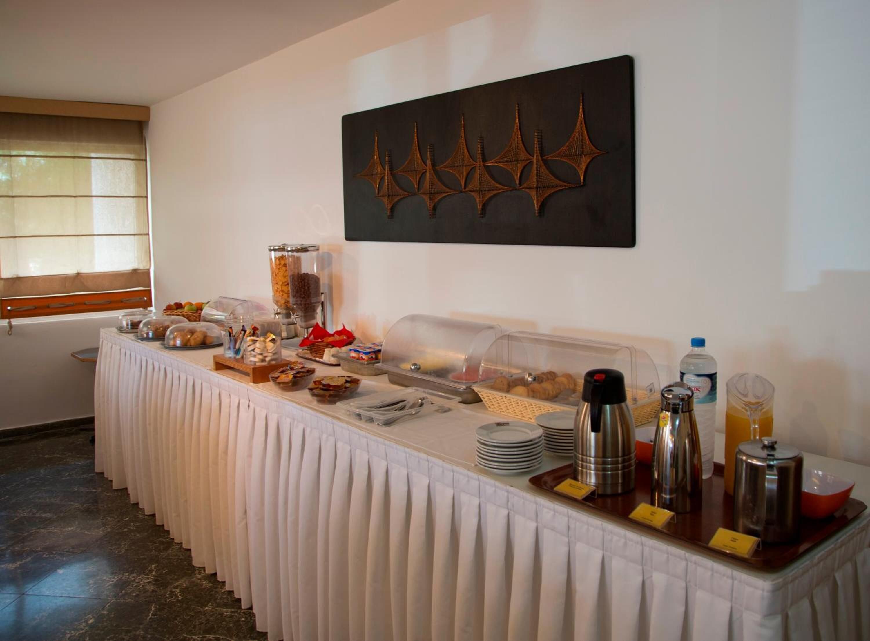 A buffet setup with various food items, a coffee station, and a decorative wall piece.
