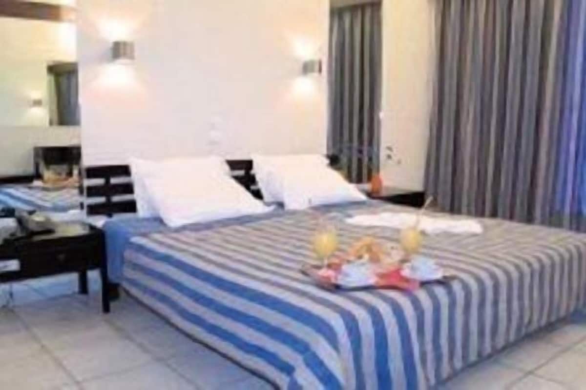 A hotel room with a bed, bedside tables, and a window with curtains.