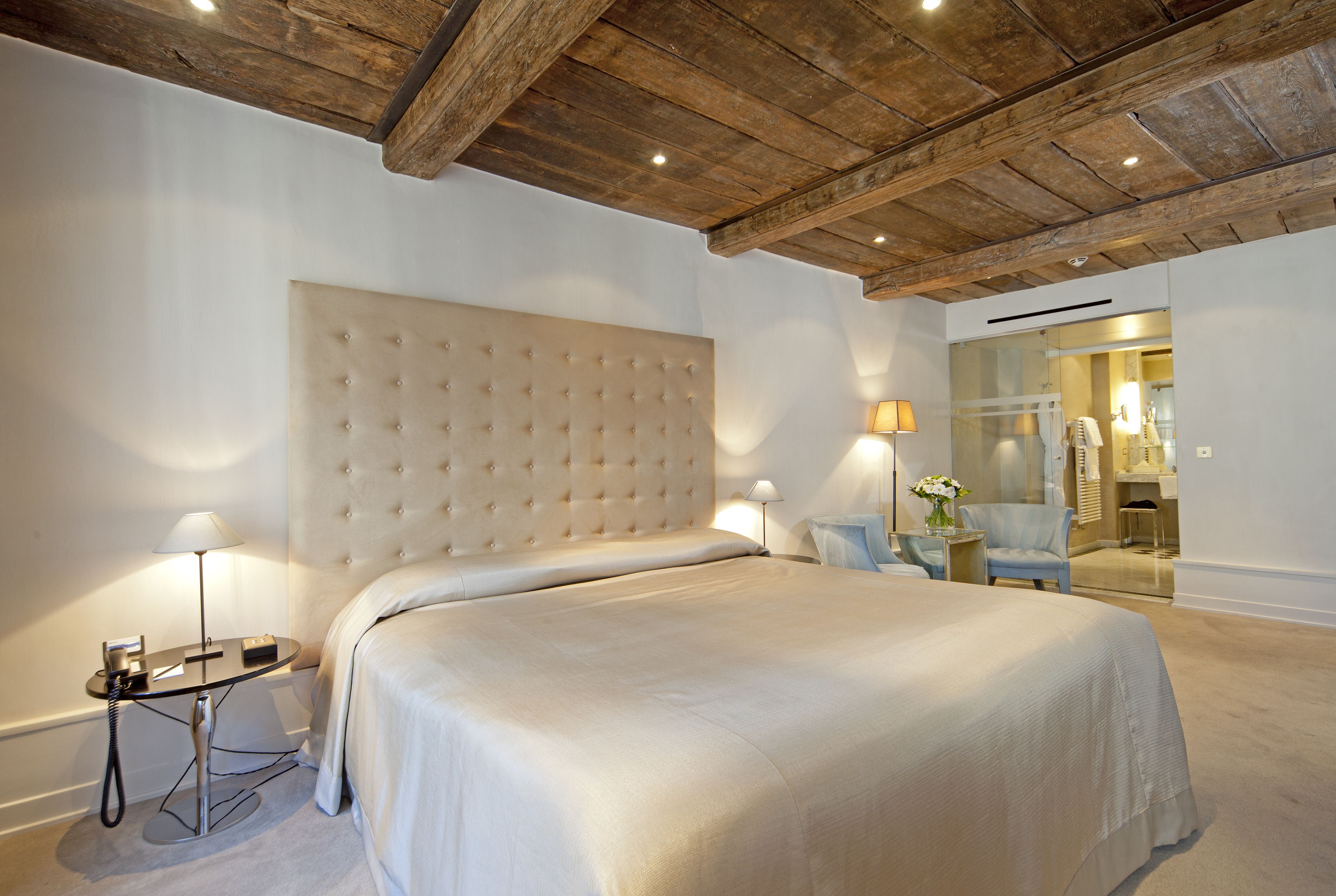 Une chambre avec un grand lit, une table de chevet avec une lampe et un plafond en bois.