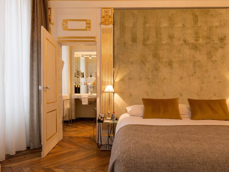 Une chambre d’hôtel avec un grand lit, une table de chevet, une lampe et un miroir.