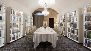 Una biblioteca con una larga mesa dispuesta para comer, rodeada de estanterías.