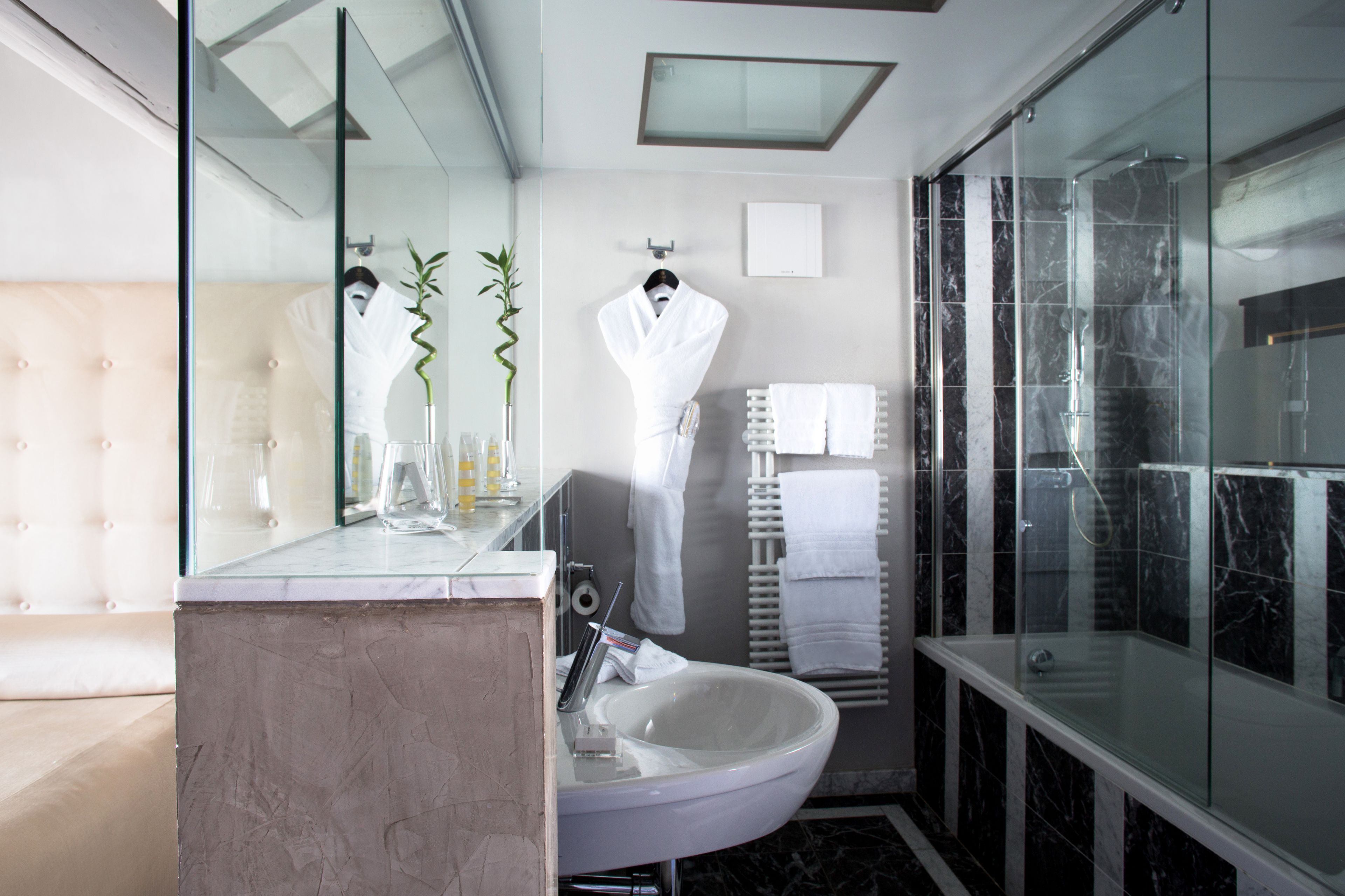 A modern bathroom with a glass-enclosed shower, a white sink, and a mirror.
