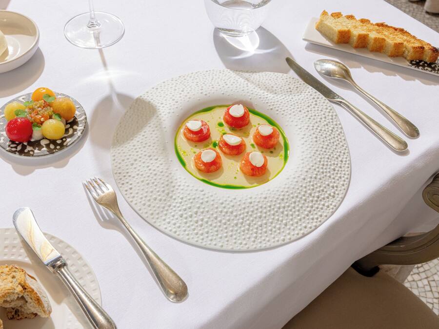 A dining table with a white tablecloth, a plate of food, cutlery, and a glass of water.