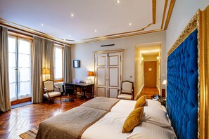 A hotel room with a large bed, two armchairs, a desk, and a wardrobe. - Hotel Le Place d'Armes - Relais & Châteaux (Luxembourg City)