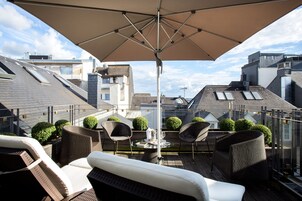 A rooftop terrace with a table, chairs, and an umbrella.