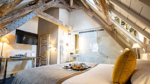 Habitación de hotel con cama, escritorio, televisor de pantalla plana y baño visible a través de una puerta abierta.
