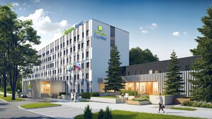Un bâtiment de la chaîne Holiday Inn Express, doté d’un design moderne, avec un grand hall d’entrée, un espace extérieur aménagé pour s’asseoir et des jardins paysagers.