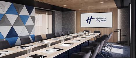A conference room with a long table, chairs, and a screen displaying the Holiday Inn Express logo.
