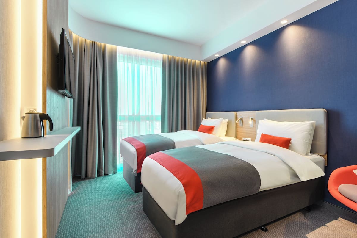A hotel room with two beds, a flat-screen TV, a coffee maker, and a view of the outdoors.