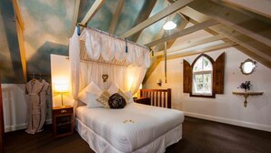 Ein Schlafzimmer mit Baldachinbett, Nachttisch, Bademantel, Fenster und einer Wandablage.