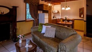 Ein gemütliches Wohnzimmer mit Holzboden, einer Couch, einem Couchtisch und einem Kamin.