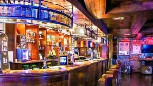 A bar with a curved counter, stools, and a variety of bottles and glasses. - The Commercial Hotel (Wishaw)