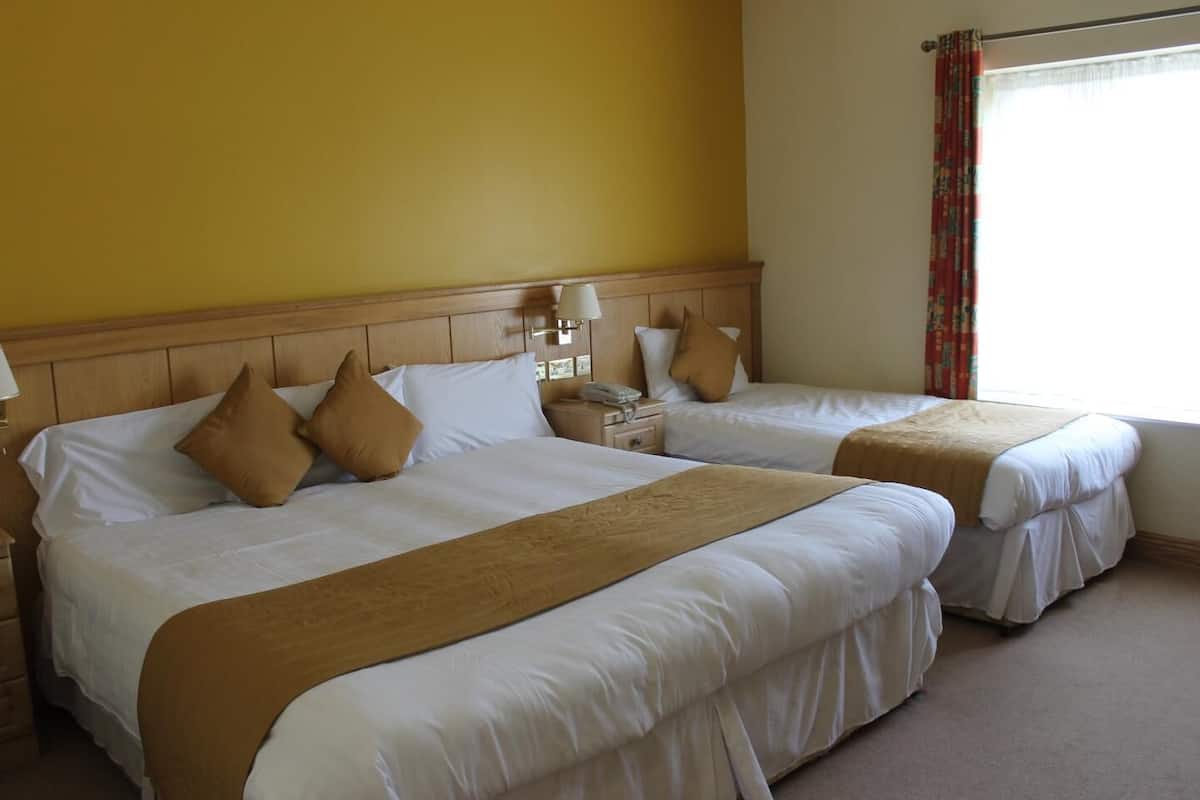 A hotel room with two beds, each with white linens and brown headboards. There are bedside tables with lamps and a telephone.