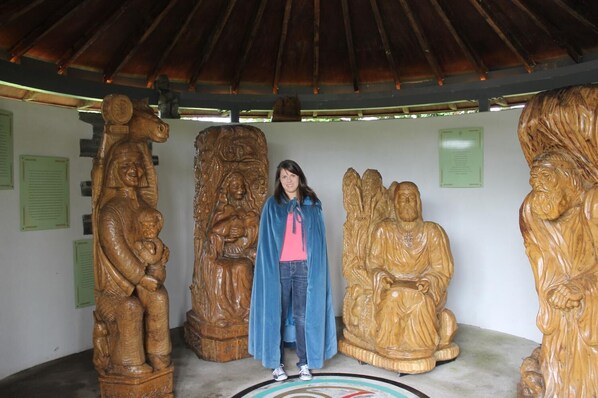 A person standing in front of a series of wooden sculptures.