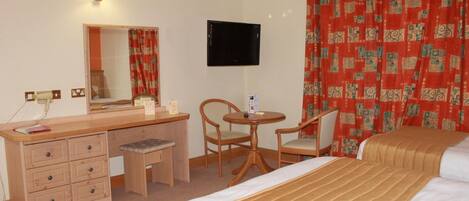 A hotel room with a bed, a desk with a chair, a television, and a mirror.