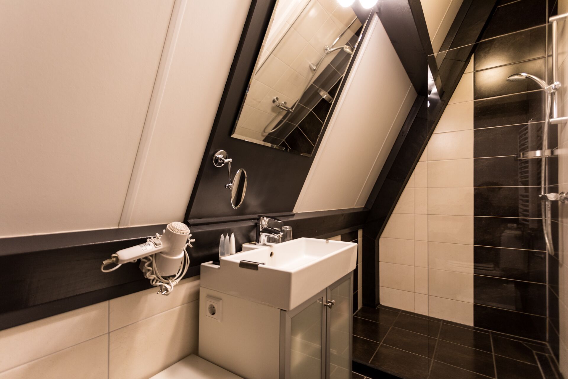 Une salle de bain moderne avec un grand miroir, un lavabo blanc et un espace douche.
