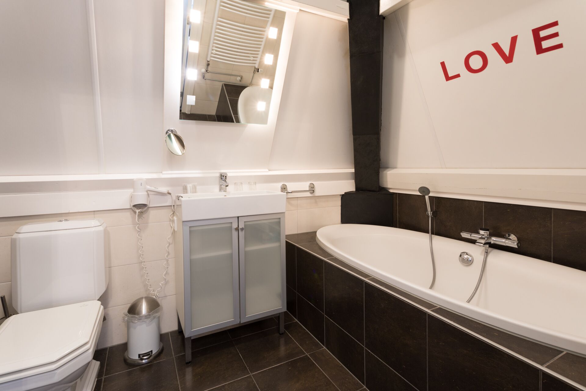 A modern bathroom with a vanity, toilet, and bathtub.