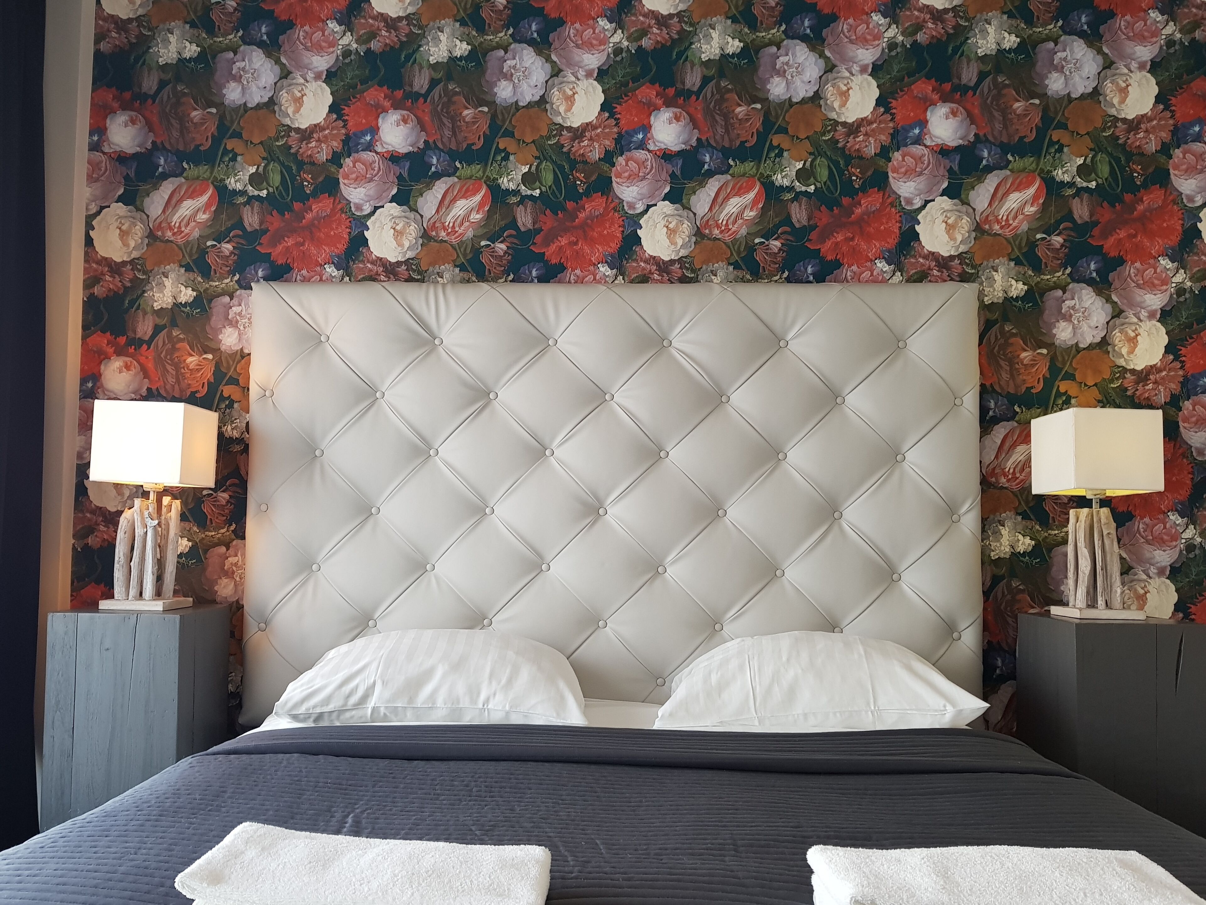 A bed with a tufted headboard, white pillows, and a dark quilted bedspread.