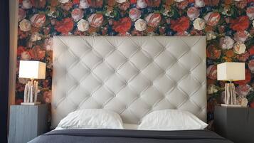Un lit avec une tête de lit capitonnée, des oreillers blancs et une couvre-lit matelassée de couleur foncée.