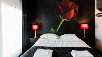 Una habitación de hotel con una cama grande, dos lámparas de noche y una decoración de rosas en la pared.