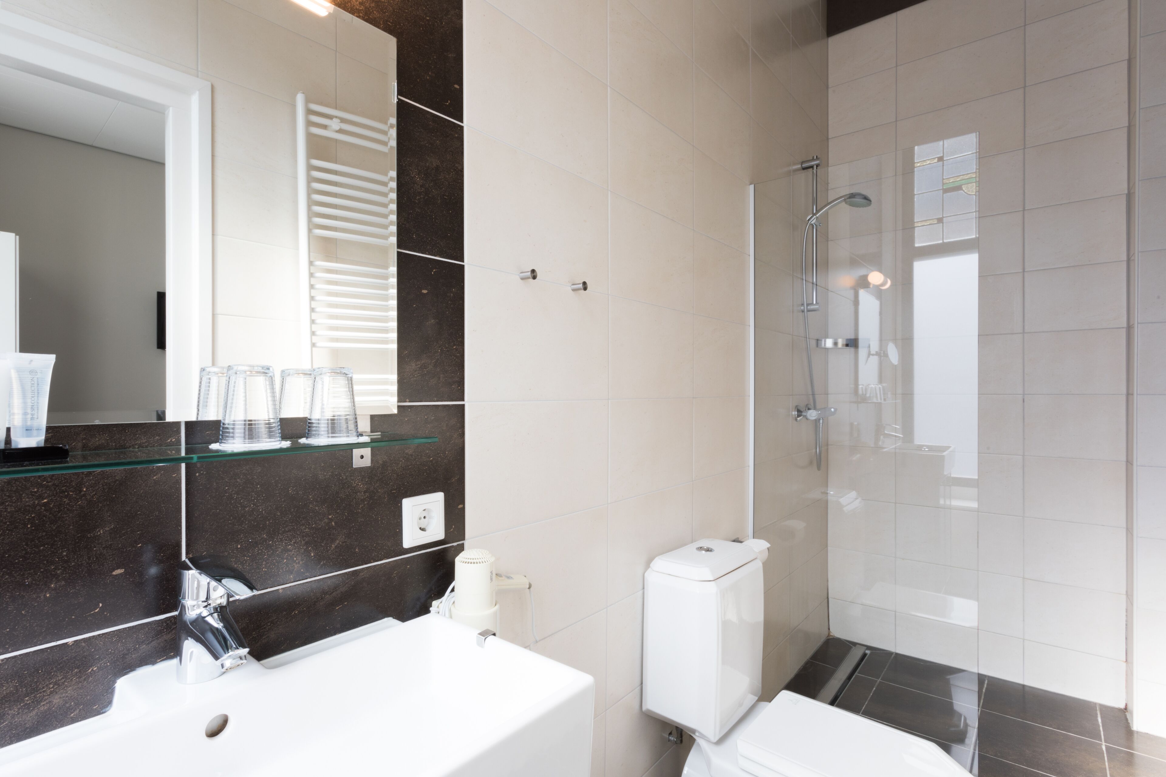 Een moderne badkamer met een douchecabine van glas, een wit wastafelmeubel en een toilet.