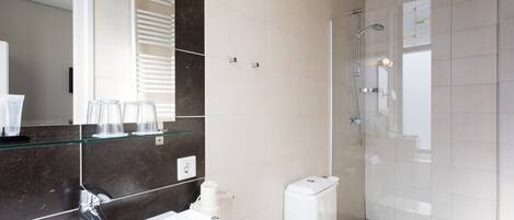 A modern bathroom with a glass shower enclosure, a white sink, and a toilet.
