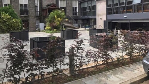 Un edificio con una mezcla de arquitectura tradicional y moderna, que presenta una fachada de piedra curva y una estructura de vidrio contemporánea.