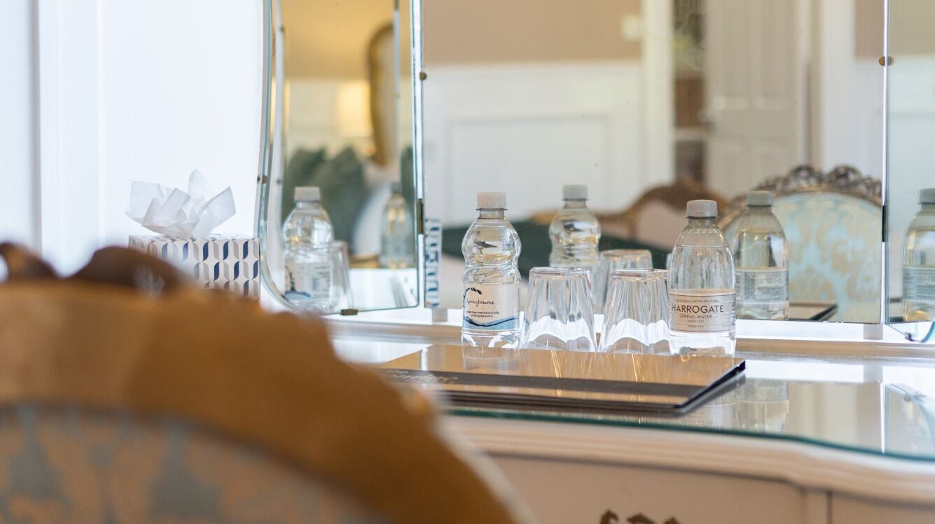 A bathroom vanity with a mirror, a tissue box, and several water bottles.