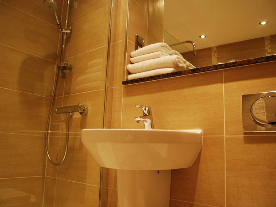 A bathroom with a sink, mirror, and shower.