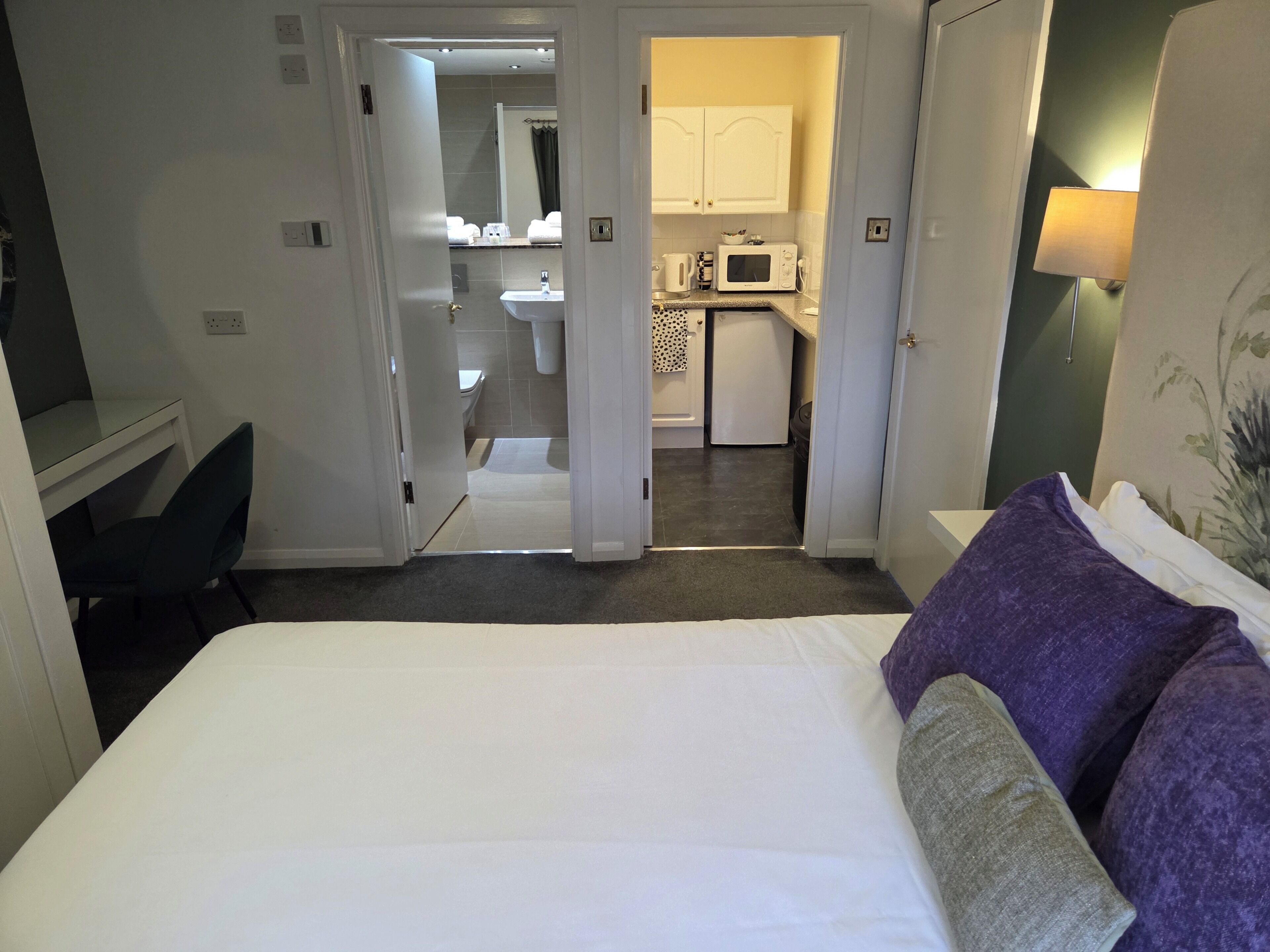 Une chambre d’hôtel avec un lit, un bureau et une vue sur la salle de bain et la cuisine.
