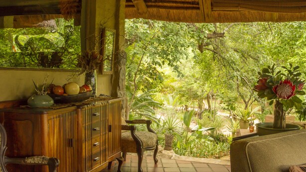 Une pièce avec un meuble en bois, une chaise et un canapé. Il y a une fenêtre donnant sur un paysage verdoyant.