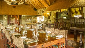 Un restaurant avec une longue table de salle à manger en bois, dressée pour un repas, et entourée de chaises.