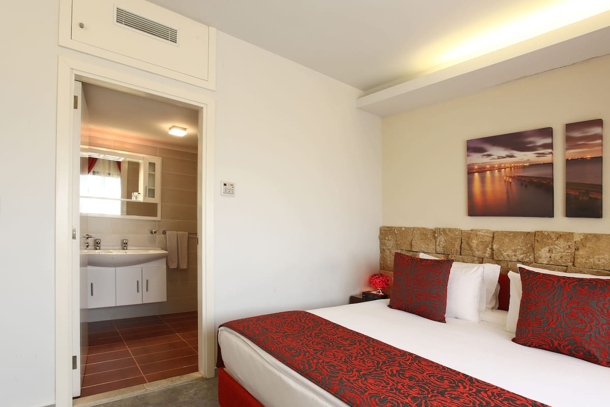A bedroom with a large bed, a headboard, a nightstand, and a wall-mounted artwork.