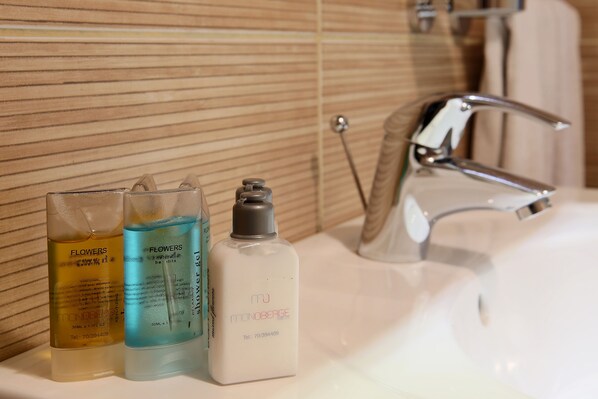 A bathroom sink with three toiletries bottles and a chrome faucet.
