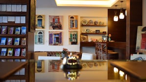 A cozy interior with a wooden bookshelf, a sofa, and a table with a decorative object. - Monoberge Byblos Hotel (Byblos)