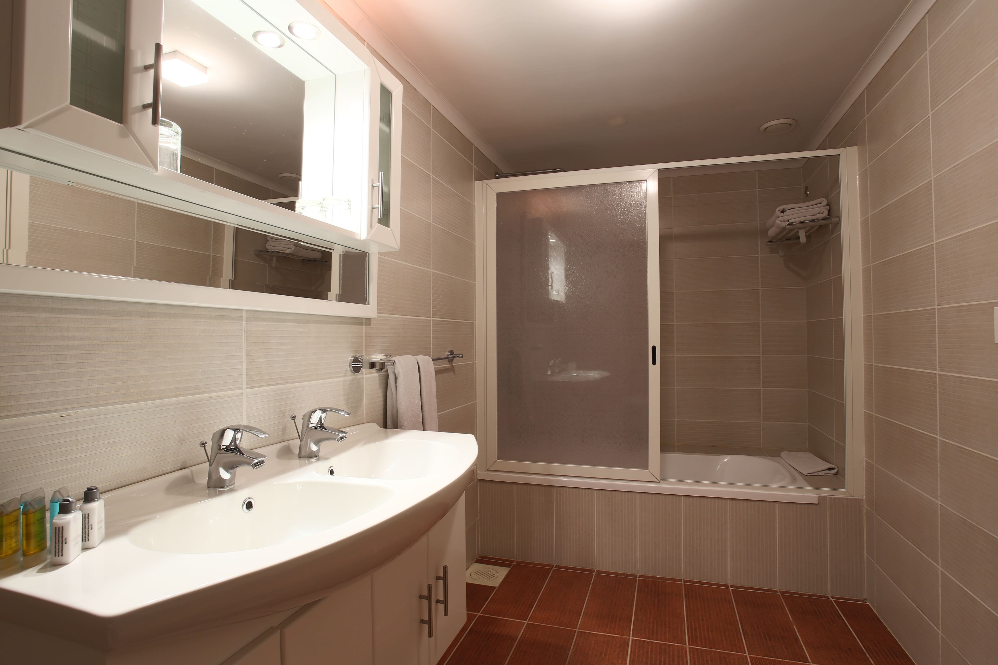 A bathroom with a double sink, a mirror, and a shower enclosure.
