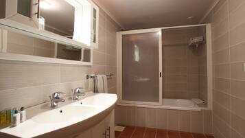 Un baño con lavamanos doble, espejo y cabina de ducha.