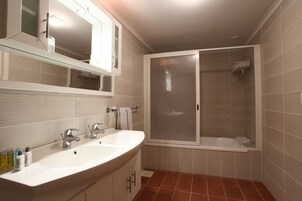 Un baño con lavamanos doble, espejo y cabina de ducha.