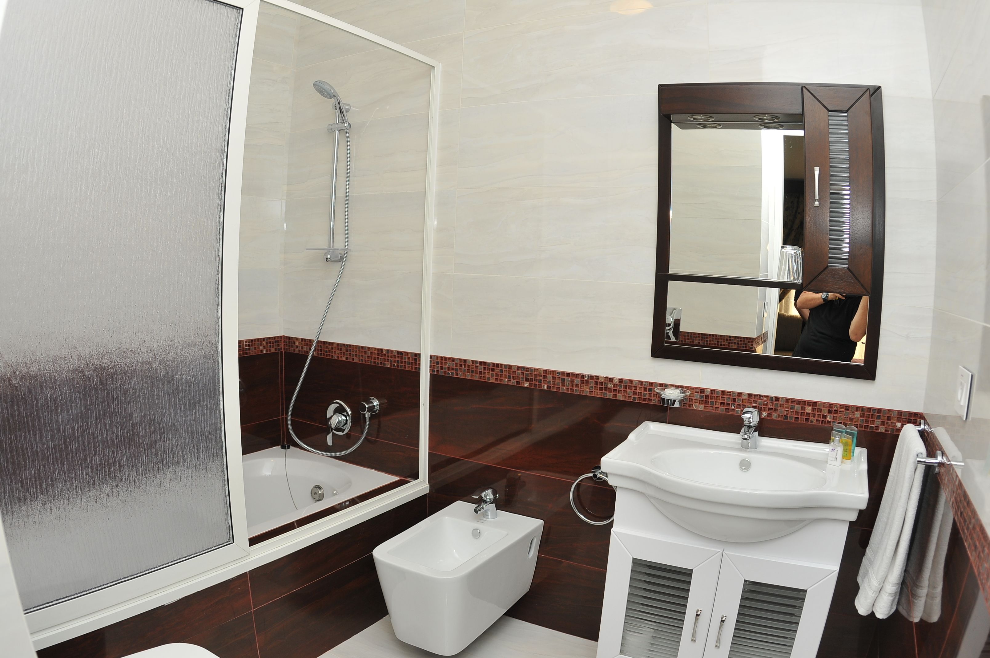 A modern bathroom with a glass-enclosed shower, a white sink, and a large mirror.