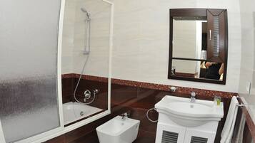 A modern bathroom with a glass-enclosed shower, a white sink, and a large mirror.
