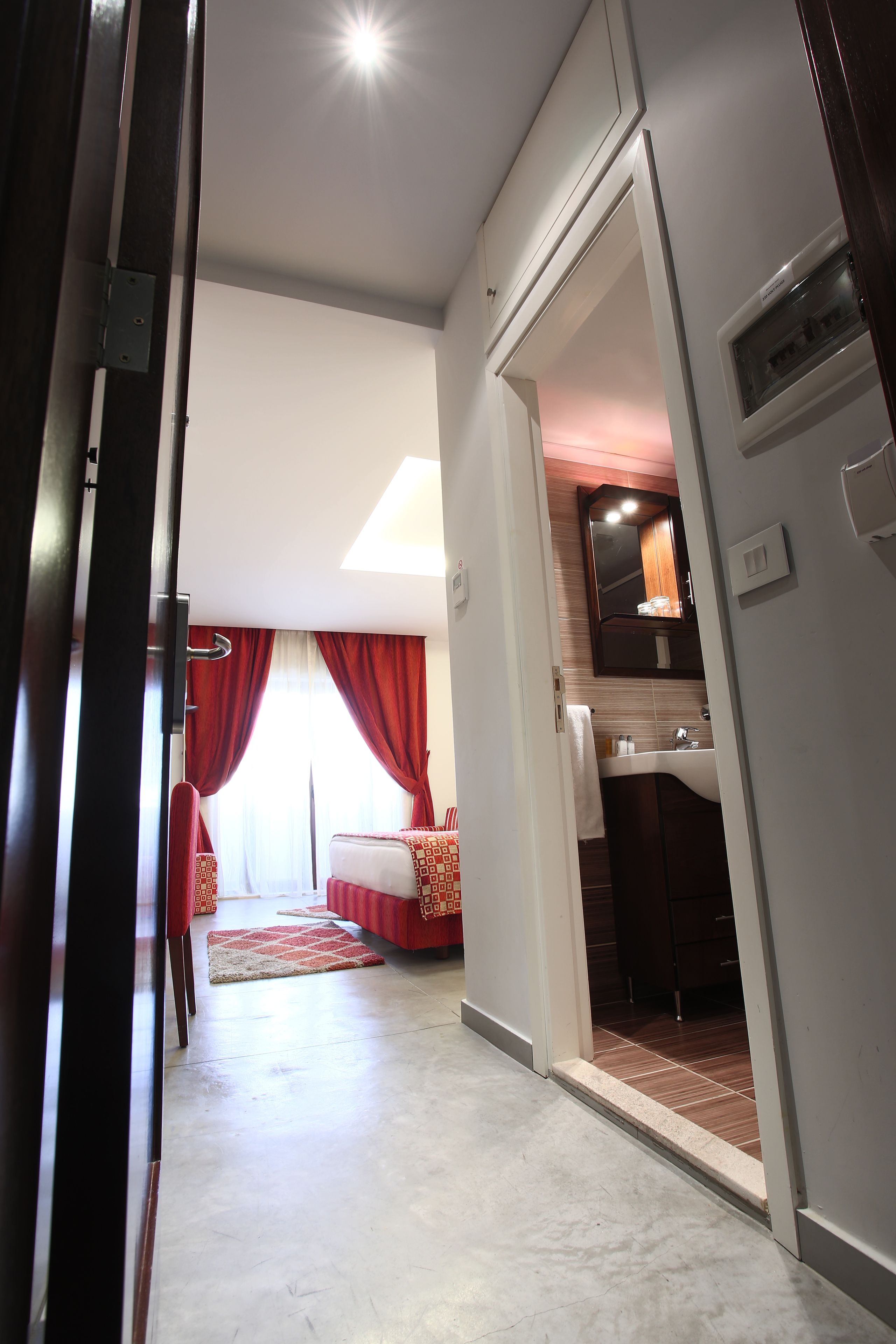 Una habitación de hotel con cama, baño y un pasillo.
