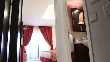 Una habitación de hotel con cama, baño y un pasillo.