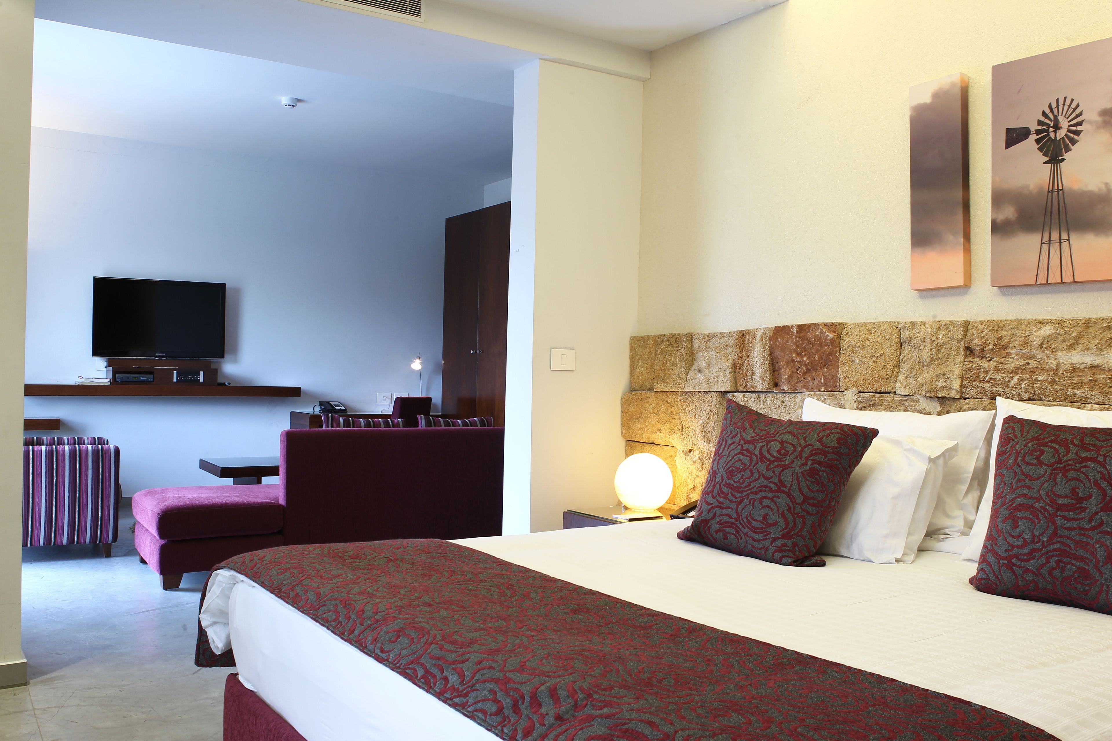 A hotel room with a bed, a TV, a desk, and a chair.