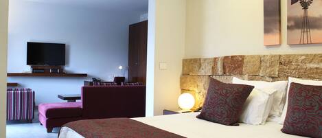 A hotel room with a bed, a TV, a desk, and a chair.